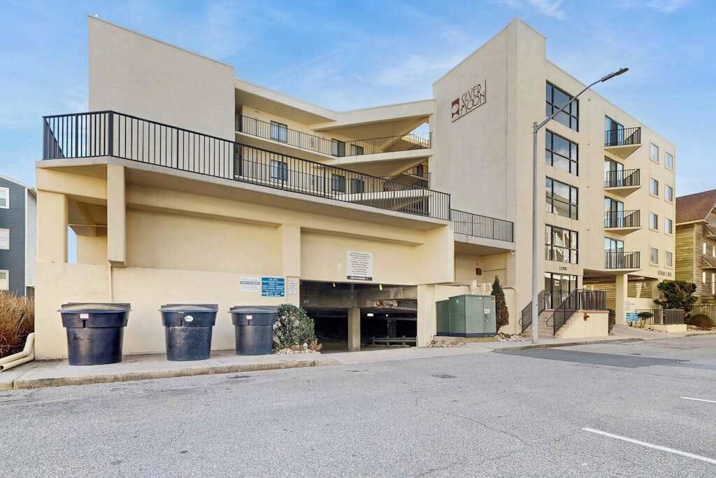 Um hotel com vários andares, fachada plana, varandas e área de estacionamento.