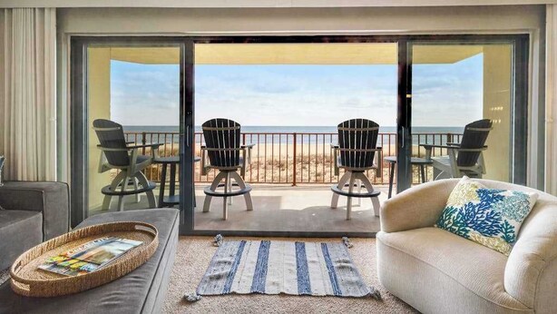 Ein Balkon mit Blick auf den Strand, eine Sitzecke und zwei Sessel.