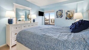 Ein Schlafzimmer mit Bett, Schminktisch und Bildern an den Wänden.