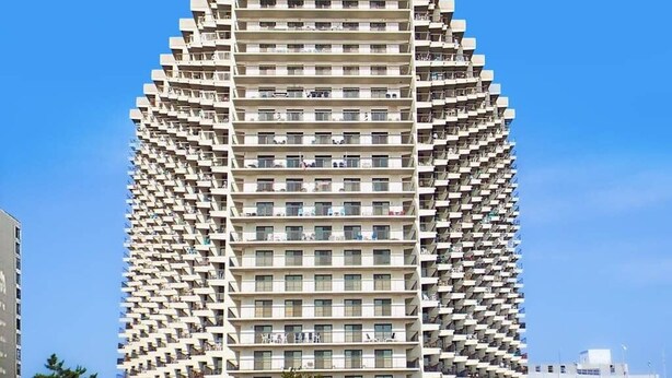 Un edifici alt amb un disseny angular únic, que destaca per nombrosos balcons i una façana uniforme.