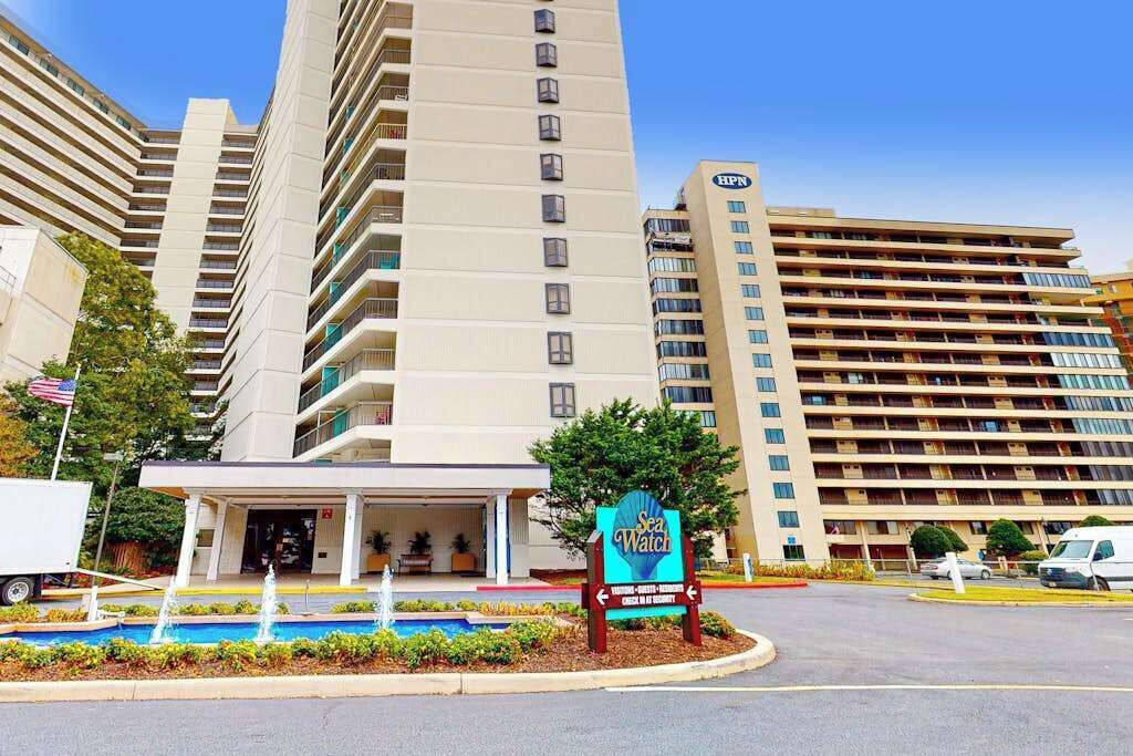A multi-story hotel with a pool area and a sign for 'Sea Watch.'