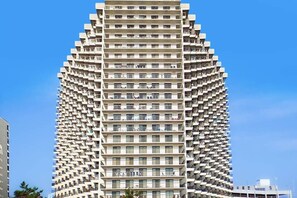 A high-rise building with a unique angular design, featuring multiple balconies and a uniform facade. - Coastal-themed beach condo with balcony, views, pools, tennis & central AC (Ocean City)