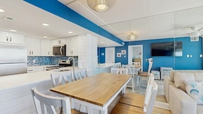 Eine moderne Küche mit weißen Schränken, einem Holztisch und einer blauen Akzentwand.