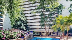 Ein modernes Hotel mit Pool, umgeben von üppiger Vegetation und blühenden Pflanzen.