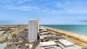 A tall hotel with a parking lot, beach, and ocean view. - Stunning beachfront condo with balcony, pools, game room, sauna & gym (Ocean City)