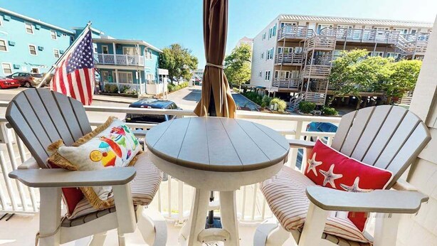 Un balcon avec deux fauteuils Adirondack, une petite table ronde et un drapeau américain.