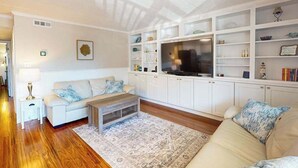 Un salon comprenant un canapé, une table basse, un téléviseur et des étagères intégrées.