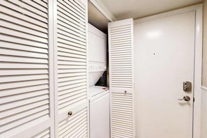 A white room with a closed door, a white wall, and a white ceiling. - Salty Sands II 103 (Ocean City)