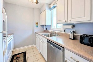 A kitchen with white cabinets, a dishwasher, a coffee maker, and a toaster. - Wight Bay North 442 (Ocean City)