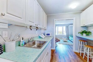 A modern kitchen with white cabinets, a stainless steel sink, and a microwave. - Bayshore Central 44 (Ocean City)