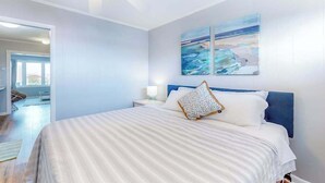 Ein Schlafzimmer mit Bett, Nachttischen, Deckenventilator und Kunstwerk an der Wand.