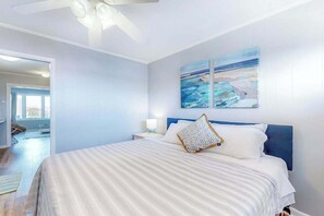 A bedroom with a bed, nightstands, a ceiling fan, and artwork on the wall. - Bayshore Central 44 (Ocean City)