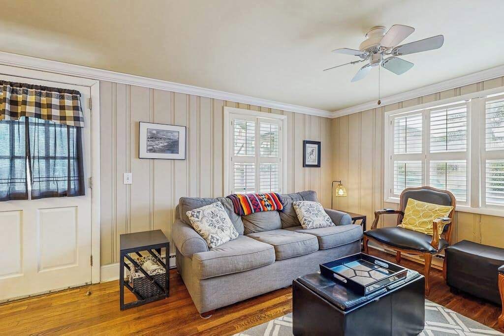 A living room with a sofa, a chair, a coffee table, and a ceiling fan.