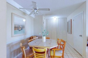 Un coin repas avec une table ronde, des chaises, un ventilateur de plafond et un tableau encadré au mur.