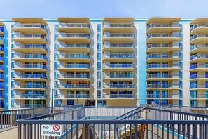 Un hôtel à plusieurs étages, doté de balcons, d’un panneau indiquant qu’il est interdit de fumer et offrant une vue sur un ciel dégagé.