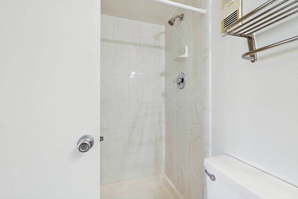 A bathroom with a shower, toilet, and towel rack.