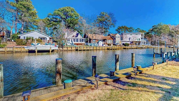 A waterfront property with dock access, houses along the water, and a boat moored nearby. - Sun-filled coastal retreat near beaches with waterfront views (Ocean City)