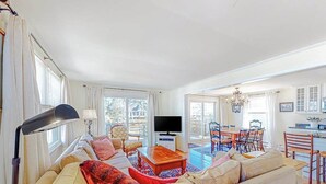 A spacious living room with a sofa, television, and dining area. - Sun-filled coastal retreat near beaches with waterfront views (Ocean City)