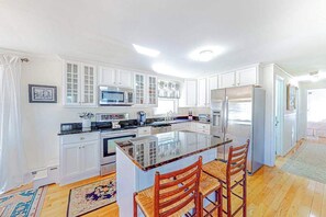 Una cocina moderna con armarios blancos, una isla central y un refrigerador.