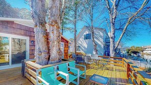 A wooden deck with outdoor seating, a large tree, and a house with a white exterior. - Sun-filled coastal retreat near beaches with waterfront views (Ocean City)