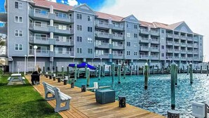 Un hôtel situé au bord de l’eau, doté de nombreux balcons, d’un quai et d’une pelouse.