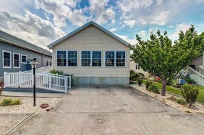 A single-story house with a front porch, a garage, and a small front yard with a tree and shrubs. - Spacious home w/ community pools, tennis, & docks - ADA compliant (Ocean City)