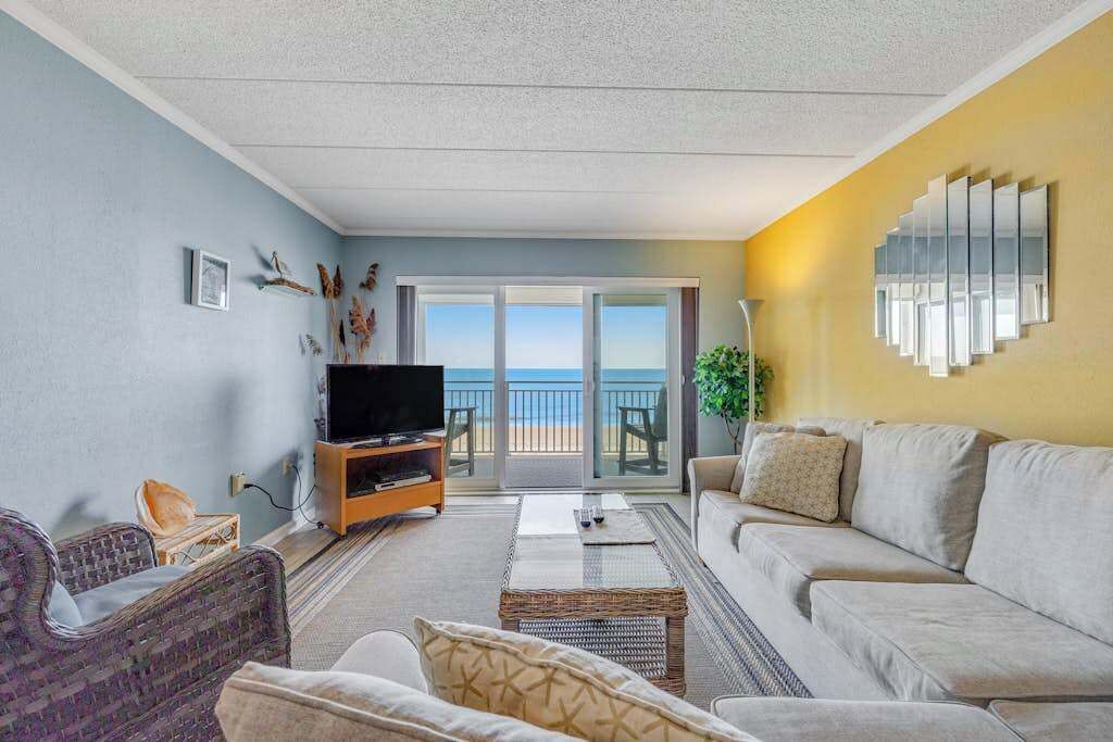 A living room with a TV, sofa, and a view to the outside.