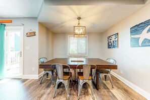 A dining room with a wooden table and metal chairs, a chandelier, and wall art. - Waterfront apartment w/ a furnished deck & free WiFi - walk to the beach (Ocean City)