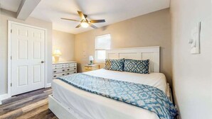 A bedroom with a bed, a ceiling fan, a dresser, a nightstand, and a window with blinds. - Waterfront apartment w/ a furnished deck & free WiFi - walk to the beach (Ocean City)