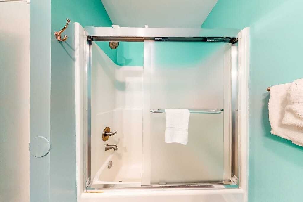 A shower enclosure with a glass door, a towel rack, and a white towel hanging on the door.
