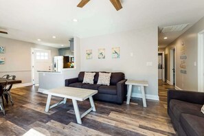 Ein modernes Wohnzimmer mit Sofa, Couchtisch und einem Essbereich mit Stühlen.