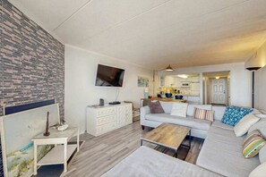 A modern living room with a sofa, coffee table, and artwork on the wall. - Oceanfront Amber Waves Condo w/Shared Outdoor Pool, AC, WiFi, W/D, Ocean View (Ocean City)
