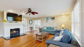 A living room with a fireplace, a sofa, a coffee table, and a ceiling fan. - Boardwalk Bungalow (Ocean City)