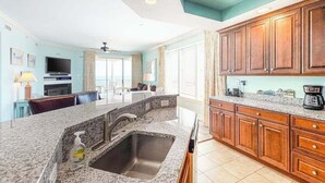 Una cocina con encimeras de granito, armarios de madera, horno integrado y un ventanal grande.