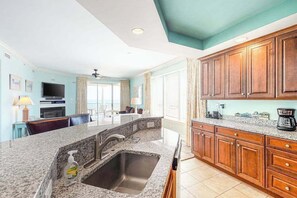 A kitchen with granite countertops, wooden cabinets, a built-in oven, and a large window. - Belmont Towers 601 (Ocean City)