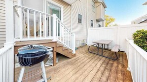 A wooden deck with a grill, a table, and a bench. - Sunset Drive townhouse with WiFi, private W/D & central AC - dog-friendly (Ocean City)