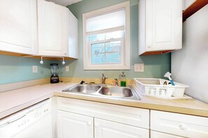A kitchen with white cabinets, a double sink, a window, and a blender on the counter. - Sunset Drive townhouse with WiFi, private W/D & central AC - dog-friendly (Ocean City)