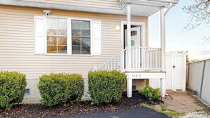 A single-story house with a front porch, a small staircase, and a mailbox. - Sunset Drive townhouse with WiFi, private W/D & central AC - dog-friendly (Ocean City)