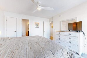 A bedroom with a bed, a dresser, a ceiling fan, and a door leading to another room. - Bridge Point   225 (Ocean City)