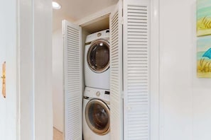 A laundry room with two stacked washing machines and a door with louvered shutters. - 124 East 304 (Ocean City)