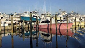 A marina with several boats docked, wooden pilings, and a clear sky. - Jocelyn Manor Unit 85 (Ocean City)