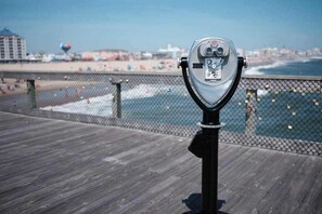 Eine Metallbeobachtungsplattform mit einem Drahtzaun, die auf einen Strand und den Ozean blickt.