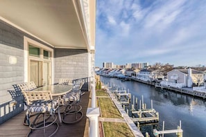 Un balcó amb una taula i cadires, amb vista a un canal que presenta docks i edificis al fons.