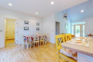 A dining area with a table and chairs, a kitchen island, and a door leading to another room. - Family-Friendly Home Close to OC w/Furnished Porch, Central A/C, & Free WiFi (Berlin)