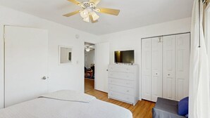 Ein Schlafzimmer mit Bett, Kommode, Fernseher und Kleiderschrank.