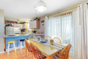 A kitchen with a dining area, a ceiling fan, and a view through the window. - Comfy & Well-Appointed Home in Oceanside Building w/Free WiFi, Central AC (Ocean City)