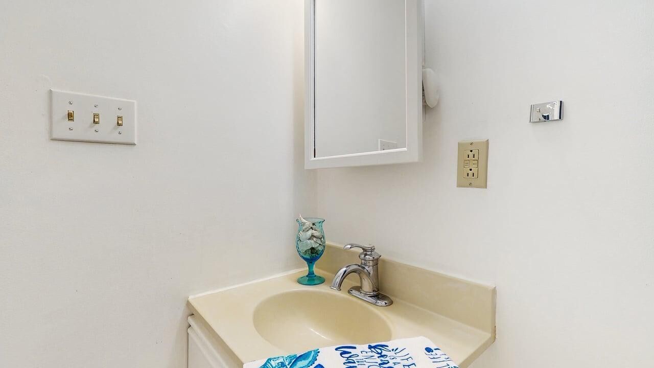 Een badkamer met een wastafel, spiegel en twee stopcontacten op de muur.