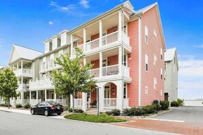 A multi-story building with balconies, a car parked in front, and a clear sky. - Sunset Island - 28 Seaside (Ocean City)
