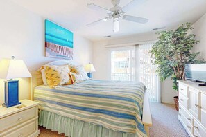 Ein Schlafzimmer mit einem Bett, zwei Nachttischlampen, einem Deckenventilator, einem Fernseher, einem Fenster mit Aussicht und einem Gemälde an der Wand.