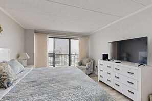 Een slaapkamer met een groot bed, een televisie, een dressoir en een balkon met uitzicht.